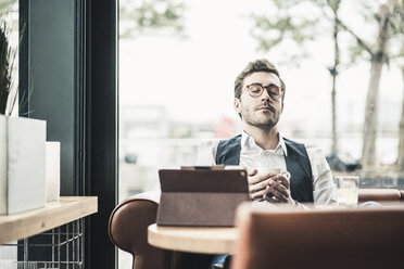 Junger Mann in einem Cafe mit Tablet Tasse Kaffee entspannt - UUF12609