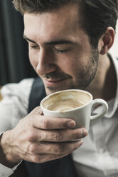 Relaxed young man drinking cup of coffee - UUF12618