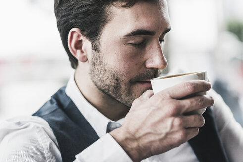 Entspannter junger Mann trinkt eine Tasse Kaffee - UUF12619