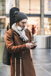 Junger Mann mit Gitarrenkoffer und Mobiltelefon - UUF12625