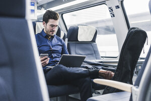 Businessman working in train using laptop - UUF12628