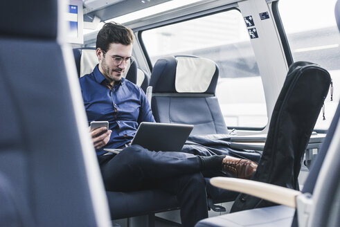 Geschäftsmann arbeitet im Zug mit Laptop - UUF12628
