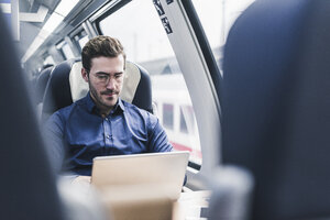 Businessman working in train using laptop - UUF12630