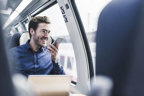 Happy businessman in train using cell phone stock photo