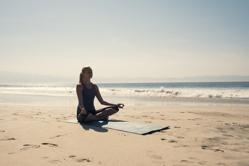 Junge Frau übt Yoga am Strand - ABAF02198