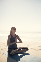 Young woman exercising yoga at a beach - ABAF02200