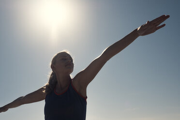 Junge Frau übt Yoga unter blauem Himmel im Gegenlicht - ABAF02201