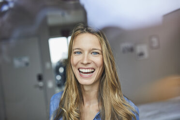 Portrait of laughing young woman behind windowpane - PNEF00423