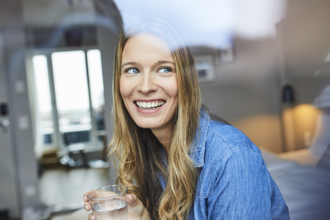 Happy young woman looking out of window stock photo