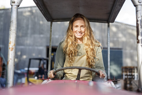 Porträt einer lächelnden Frau, die einen Traktor fährt - PESF00898