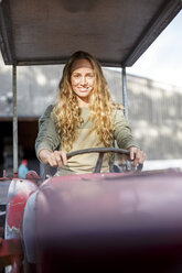 Porträt einer lächelnden Frau, die einen Traktor fährt - PESF00899
