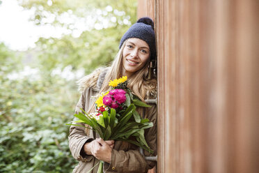 Portrait of smiling young woman holding bunch of flowers outdoors - PESF00903