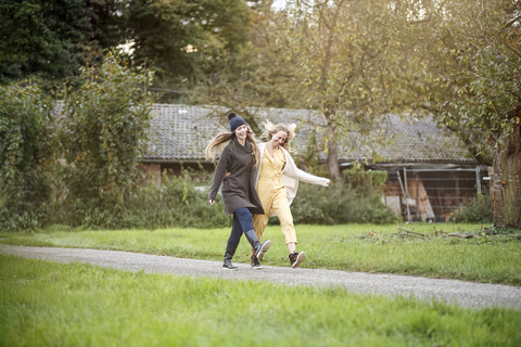 Zwei glückliche Frauen spazieren in ländlicher Landschaft, lizenzfreies Stockfoto