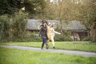 Two happy women walking in rural landscape - PESF00909