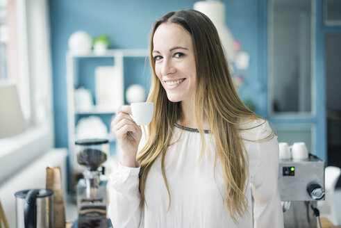 Porträt einer glücklichen Geschäftsfrau, die in der Küche eines Lofts Espresso trinkt - MOEF00716