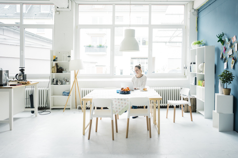 Lächelnde Frau arbeitet am Laptop in einem Loft, lizenzfreies Stockfoto