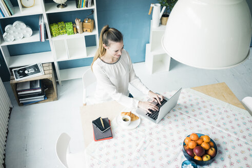 Lächelnde Frau arbeitet zu Hause am Laptop - MOEF00721