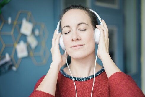 Porträt einer Frau mit geschlossenen Augen, die mit Kopfhörern Musik hört - MOEF00722