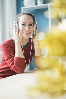 Porträt einer glücklichen Frau, die mit Kopfhörern Musik hört - MOEF00725