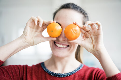 Lachende Frau, die ihre Augen mit Orangen bedeckt - MOEF00732