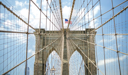 USA, New York, Brooklyn, Nahaufnahme der Brooklyn Bridge Metallkabel und Bögen mit amerikanischer Flagge an der Spitze - DAPF00874