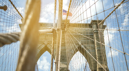 USA, New York, Brooklyn, Nahaufnahme der Brooklyn Bridge Metallkabel und Bögen mit amerikanischer Flagge an der Spitze - DAPF00875