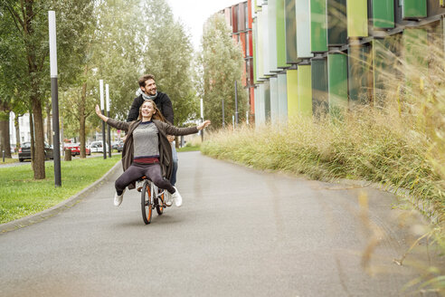 Glückliches Paar fährt auf einem Fahrrad auf einer Fahrspur - PESF00917