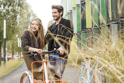 Lächelndes Paar mit Fahrrädern auf einer Fahrspur - PESF00919