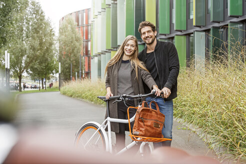 Porträt eines lächelnden Paares mit Fahrrad auf einer Fahrbahn - PESF00920