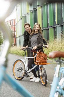 Porträt eines lächelnden Paares mit Fahrrad auf einer Fahrbahn - PESF00921