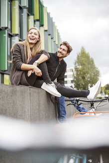 Glückliches Paar mit Fahrrädern auf einer Mauer sitzend - PESF00924