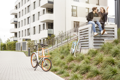 Glückliches Paar mit Fahrrädern und Laptop in städtischer Umgebung, lizenzfreies Stockfoto