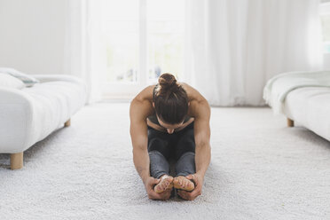 Frau sitzt auf dem Boden und übt Yoga - ASCF00788