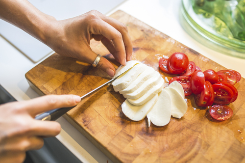 Woman preparing Caprese salad on chopping board stock photo