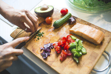 Woman preparing vegetables and salmon on chopping board - ASCF00808