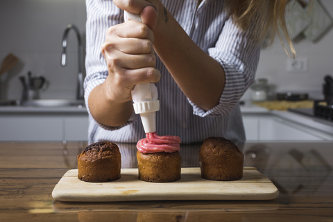 Frau bei der Zubereitung von Muffins zu Hause, lizenzfreies Stockfoto