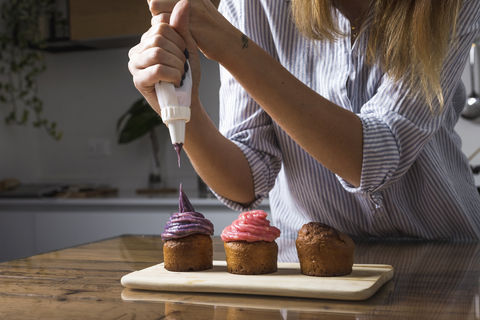 Frau bei der Zubereitung von Muffins zu Hause, lizenzfreies Stockfoto