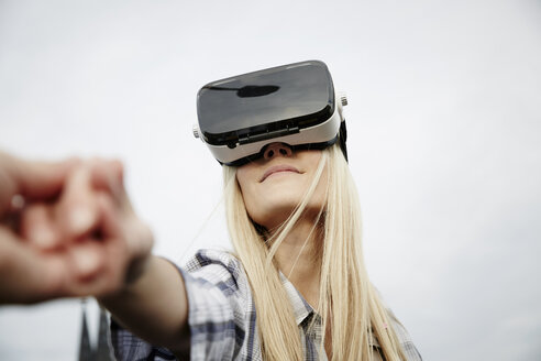 Frau mit Virtual-Reality-Brille hält Hände - FMKF04762
