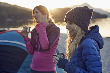 Two female friends at tent holding mugs - PNEF00427