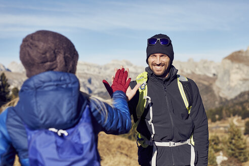 Smiling man and woman hiking in the mountains high fiving - PNEF00448