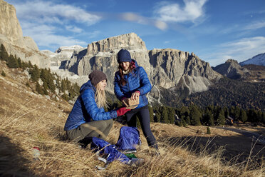 Zwei junge Frauen beim Wandern in den Bergen, die eine Pause machen - PNEF00453