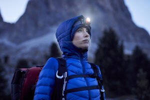 Junge Frau mit Stirnlampe in der Abenddämmerung in den Bergen - PNEF00460