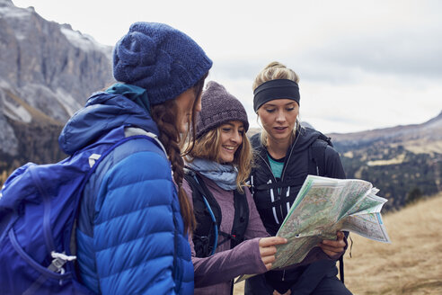 Drei junge Frauen beim Wandern in den Bergen mit Blick auf eine Karte - PNEF00462