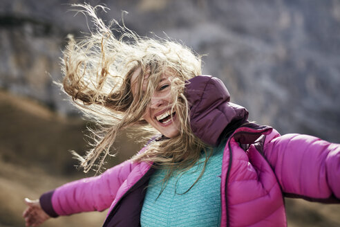 Happy young woman leaning against the wind in the mountains - PNEF00480