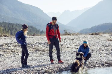 Germany, Bavaria, Karwendel, group of friends hiking with dog at the riverside - PNEF00486