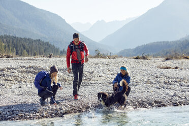 Deutschland, Bayern, Karwendel, Gruppe von Freunden beim Wandern mit Hund am Flussufer - PNEF00487