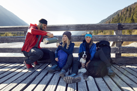 Group of friends with dog hiking resting on a bridge stock photo