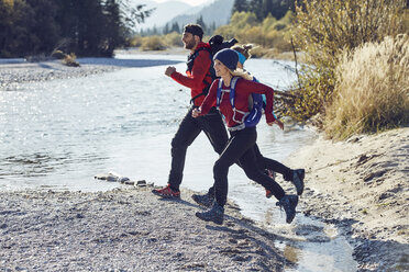 Gruppe von Freunden beim Wandern und Springen über den Fluss - PNEF00498