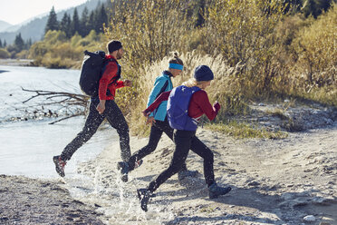 Gruppe von Freunden beim Wandern und Springen über den Fluss - PNEF00499