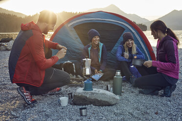 Gruppe von Wanderern, die bei Sonnenuntergang am Seeufer zelten - PNEF00503